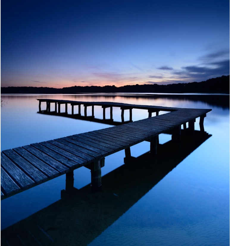 wooden pier over still water at dusk